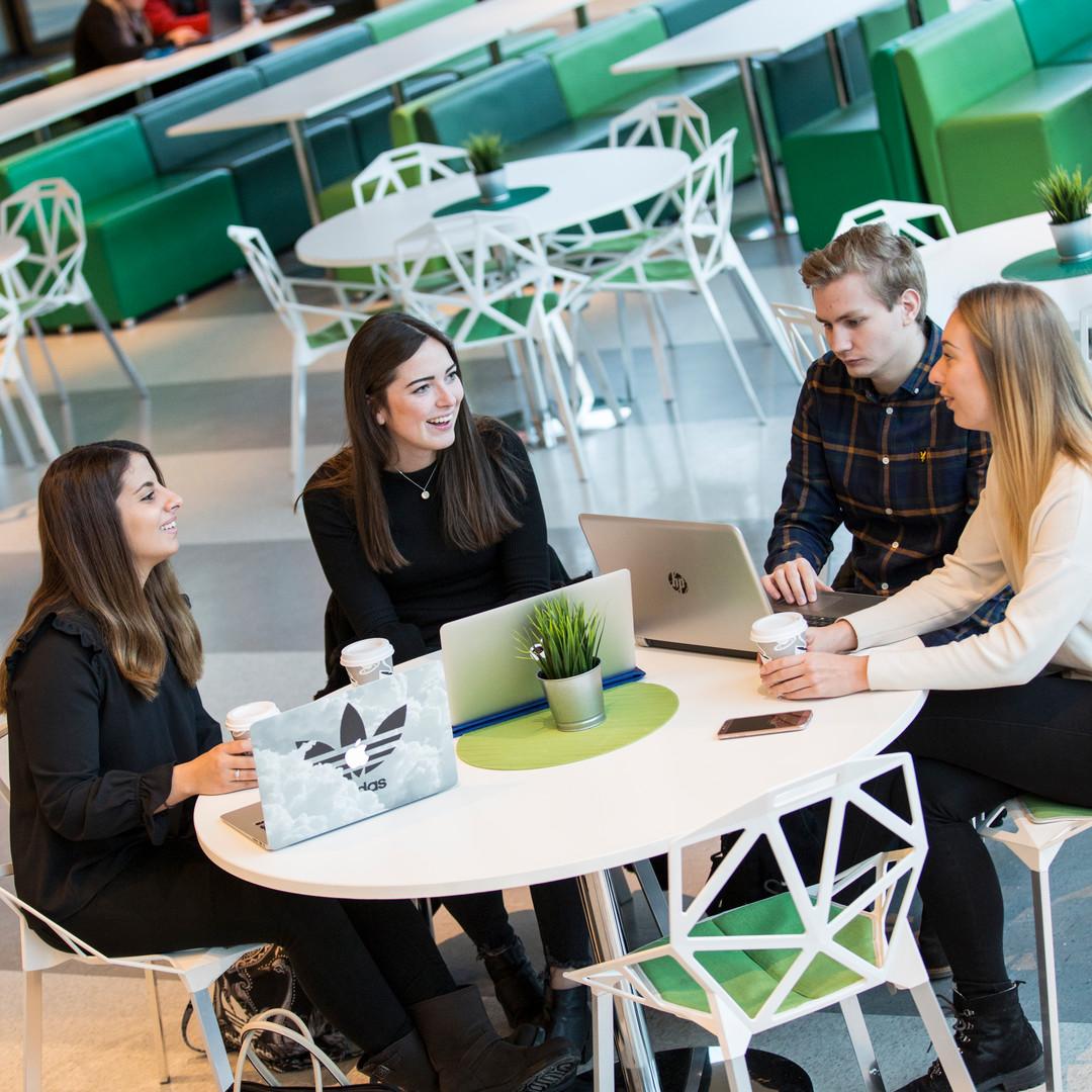 Studenter sitter vid ett bord och studerar tillsammans