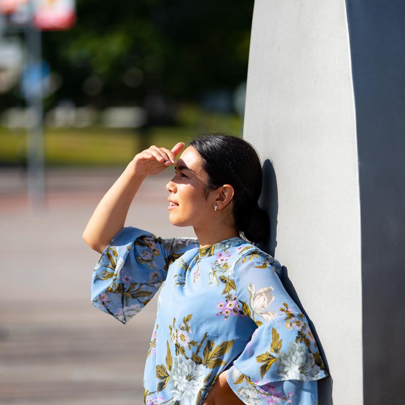 Student står i solen utanför universitetet och blickar ut över Campusområdet. 