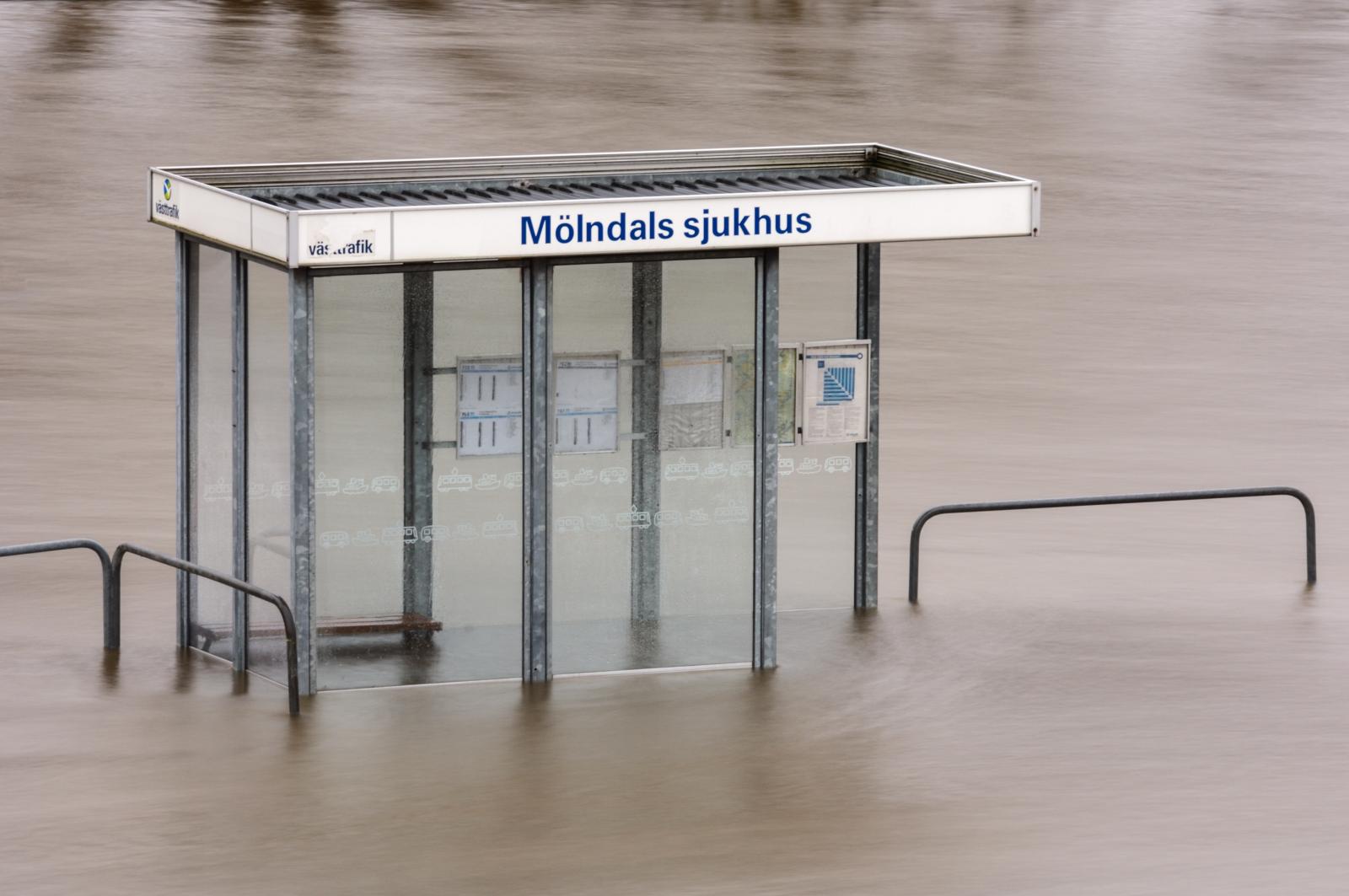 En översvämmad busskur, omgiven av vatten.