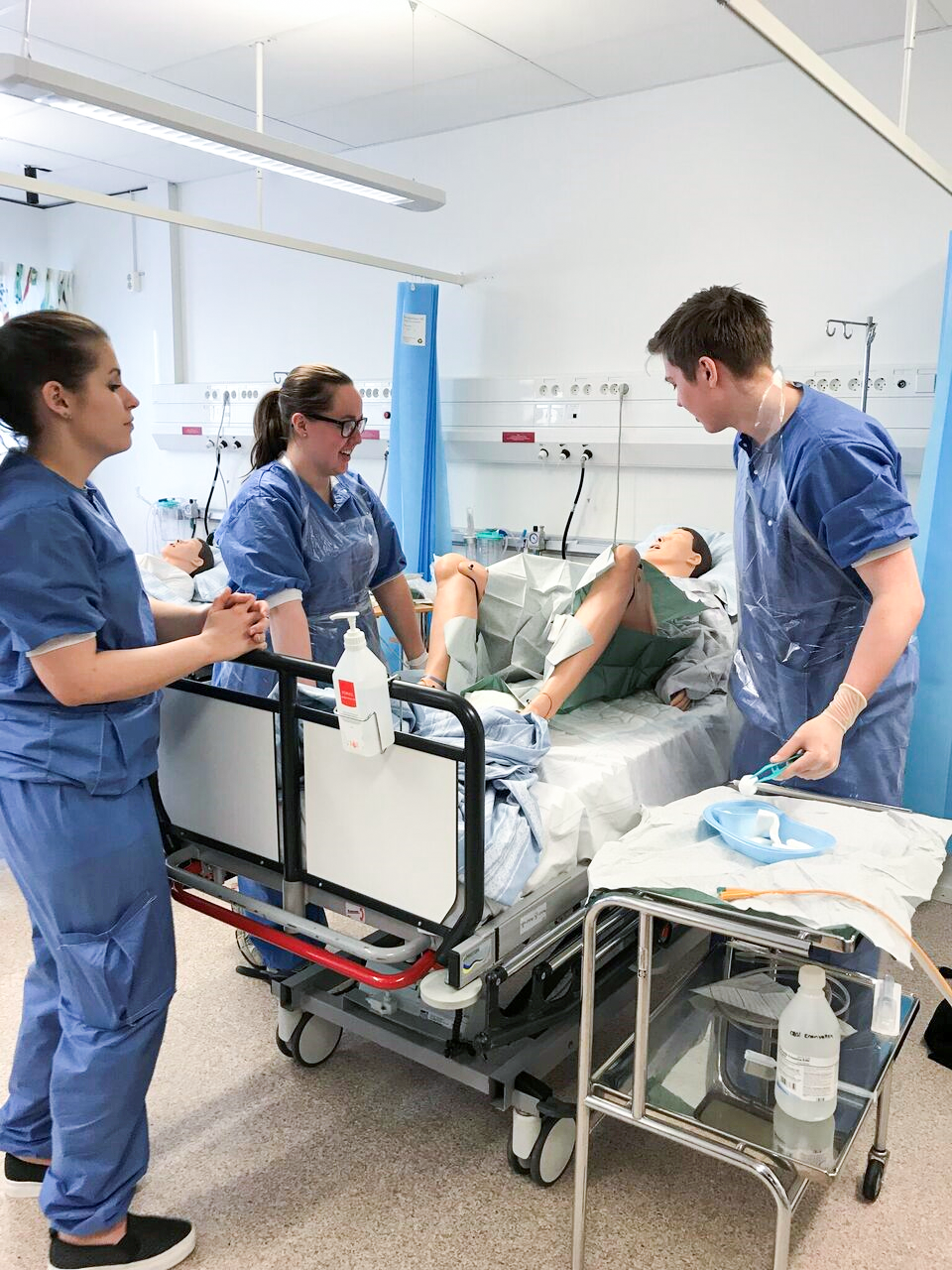 Tre sjuksköterskor står runt en patient