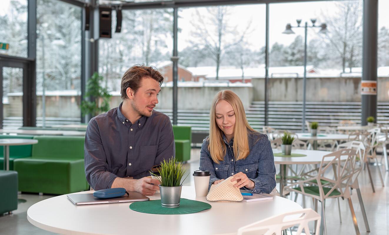 Två studenter i samtal vid ett bord