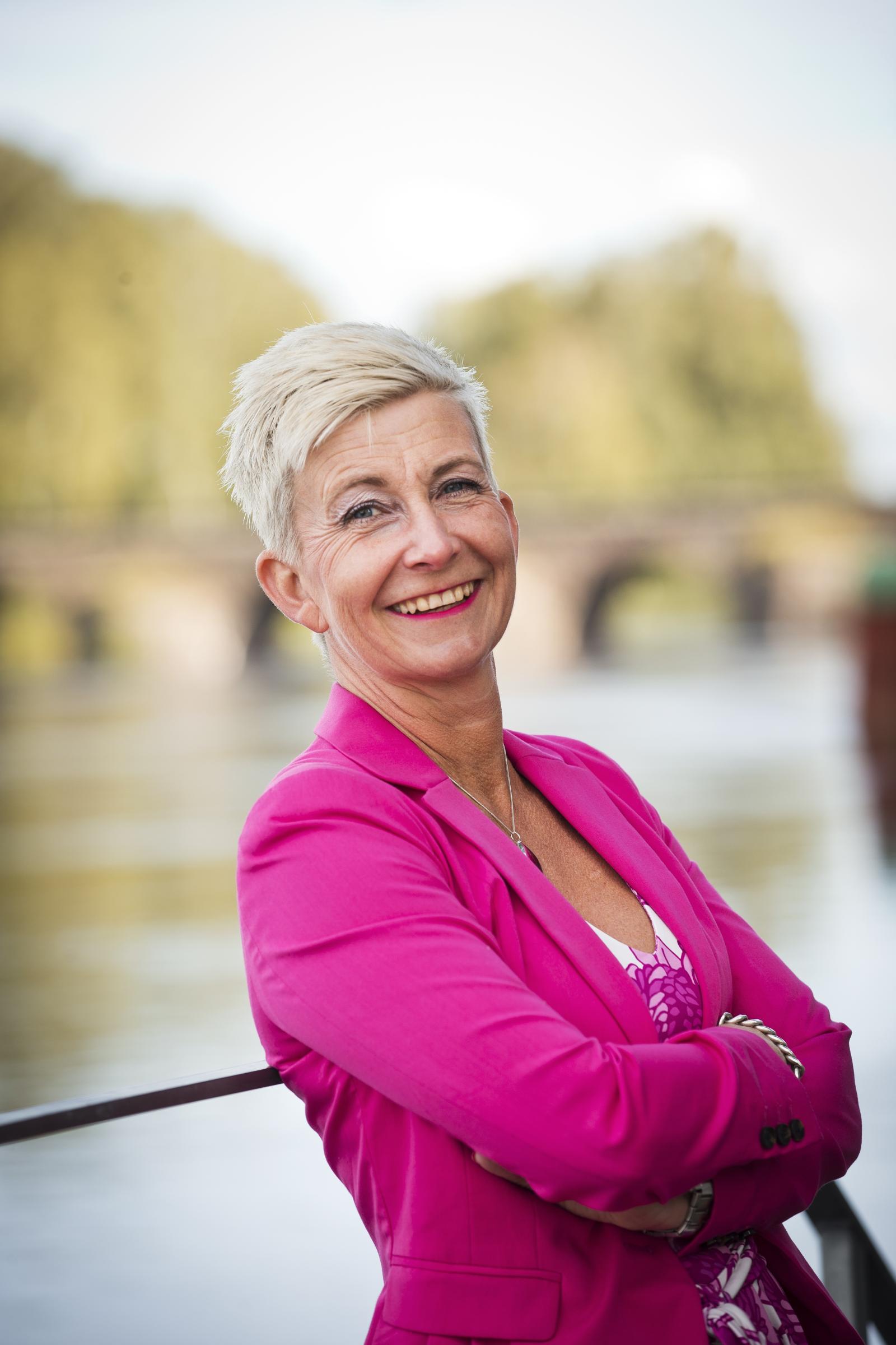 Glad blond kvinna klädd i rosa kavaj
