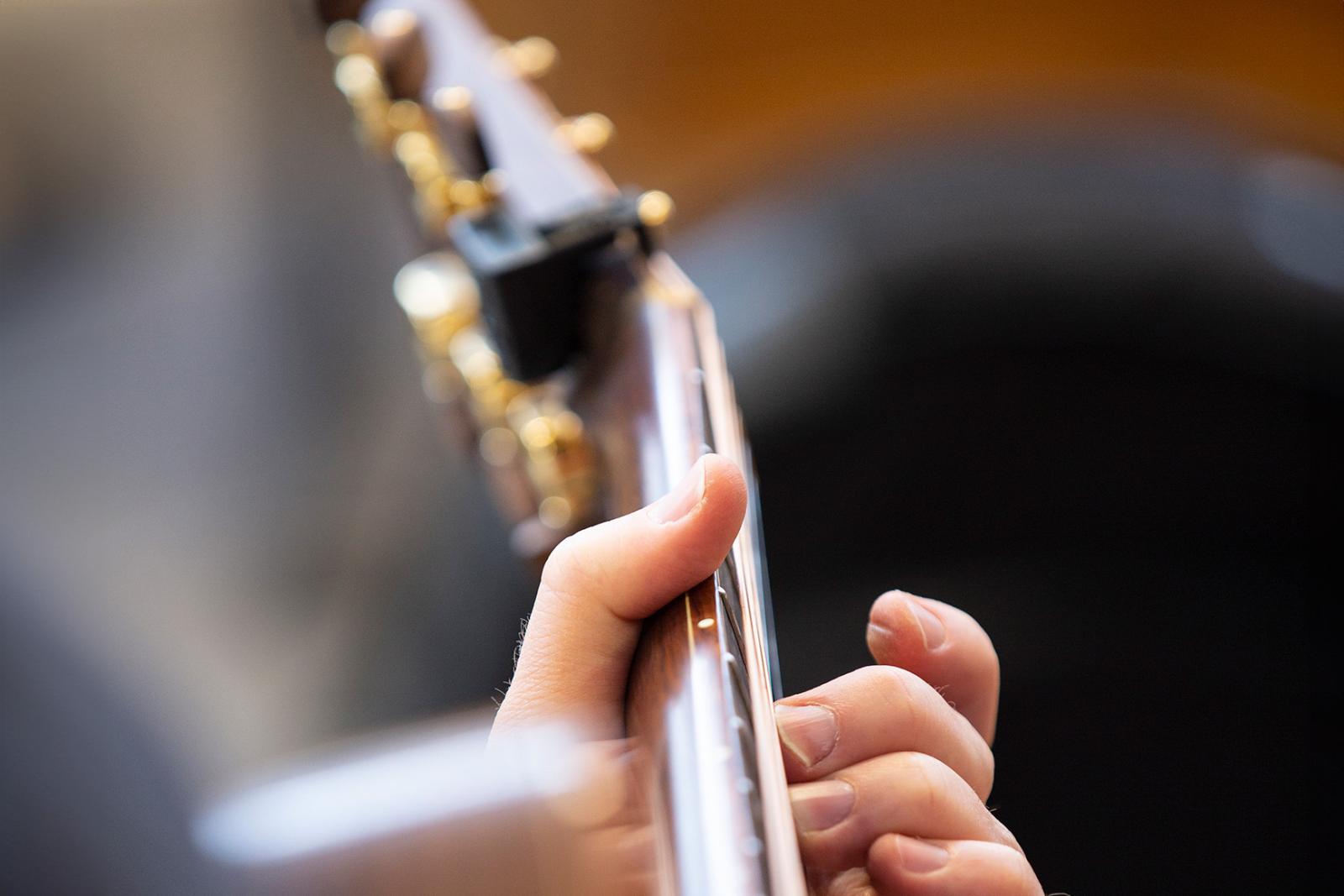 Närbild gitarr och hand