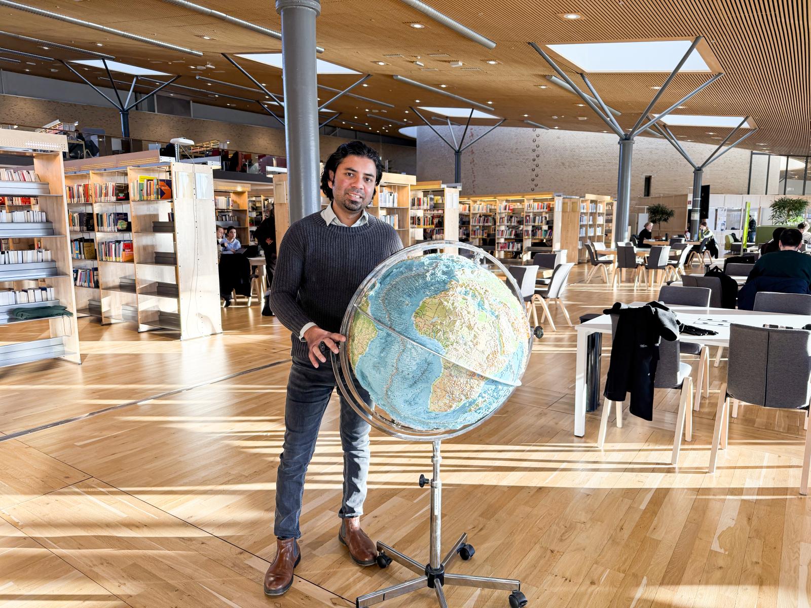 Avit Bhowmik med jordglob i biblioteket