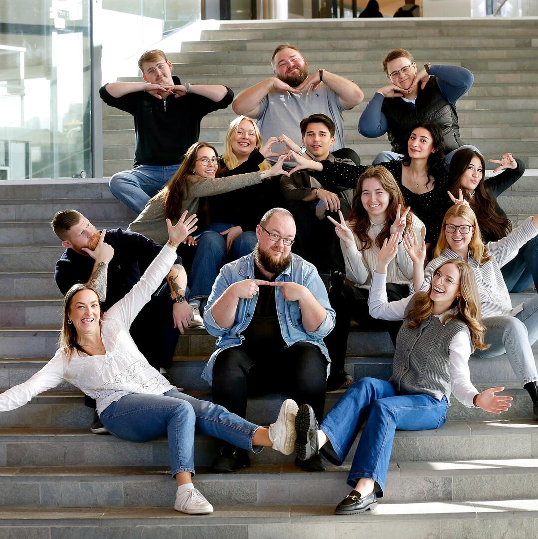 Glada studenter som sitter i trappan vid huvudentrén