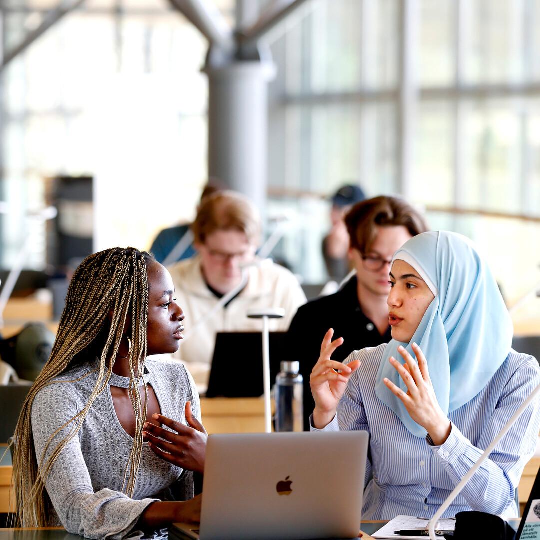 Studenter diskuterar i biblioteket