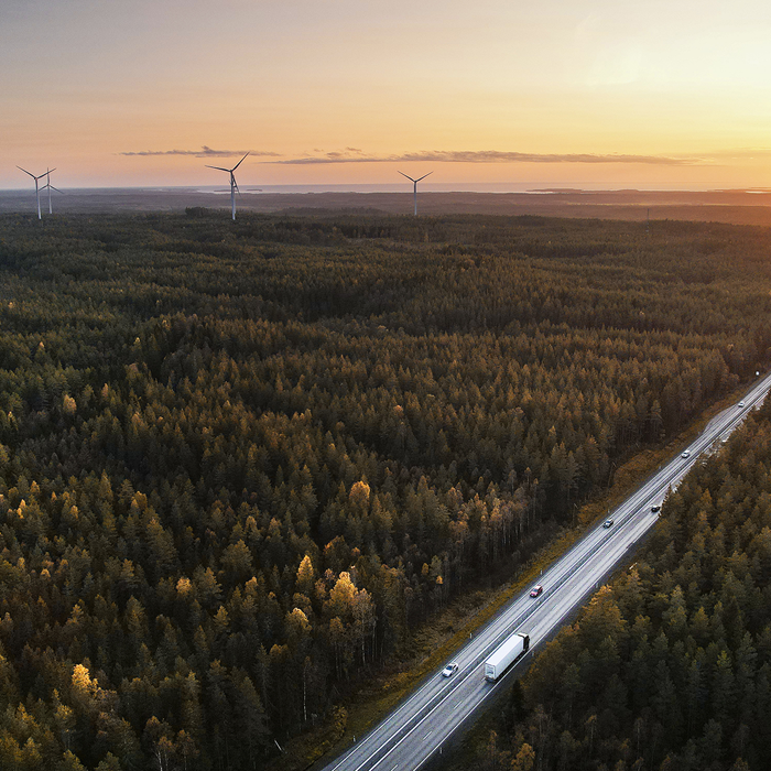 Drönarbild över skog och väg med vindkraft