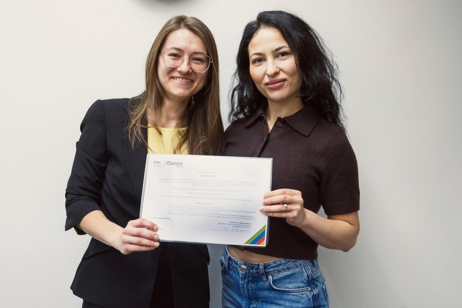 två kvinnor som håller upp ett diplom