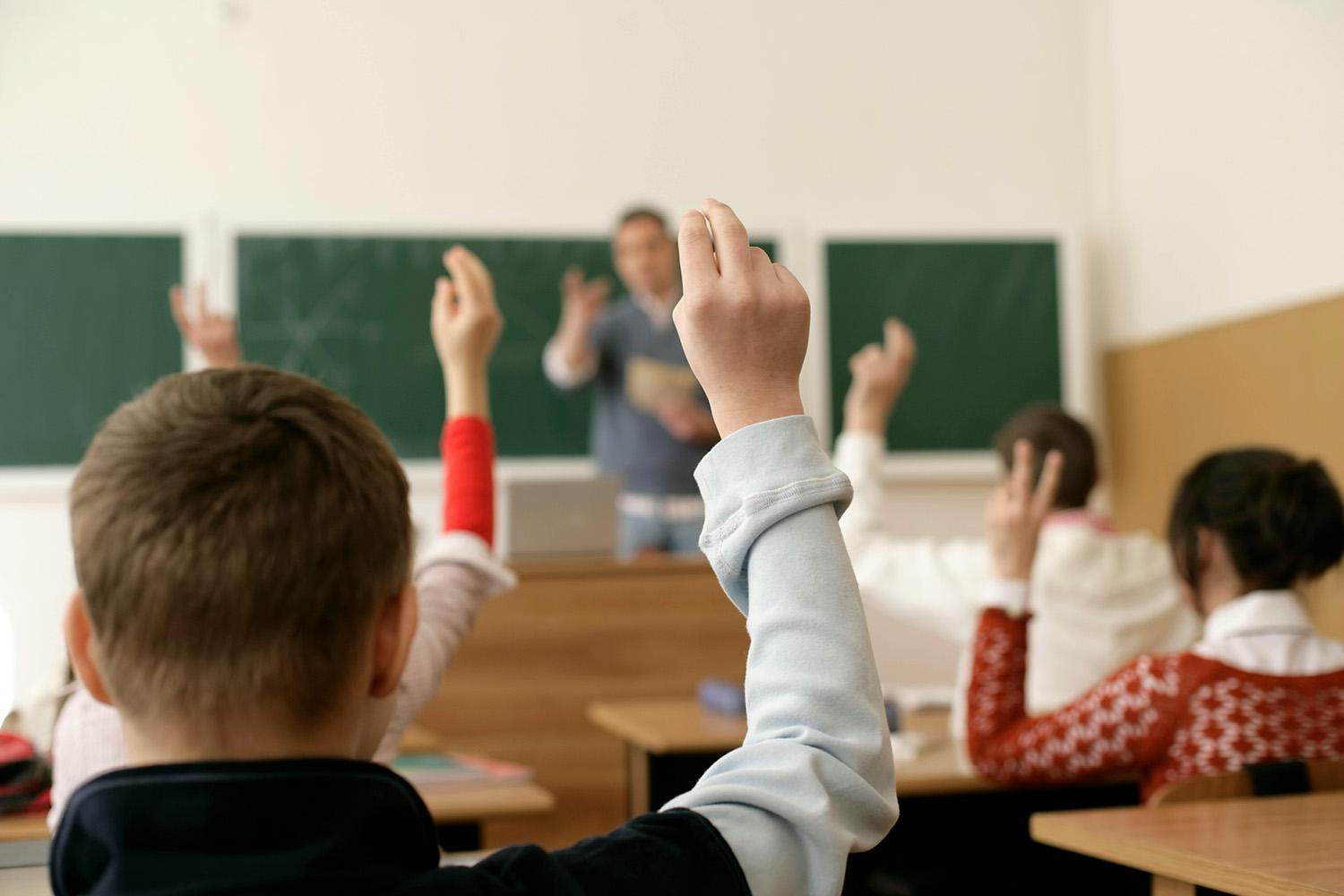 Ungdomar som räcker upp händer i ett klassrum_Avhandling om kontroversiella diskussioner om samhällsfrågor_Victoria Williamsson