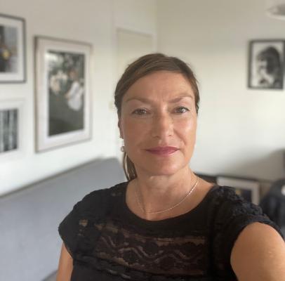 Kvinna med uppsatt hår och svart t-shirt tittar in i kameran