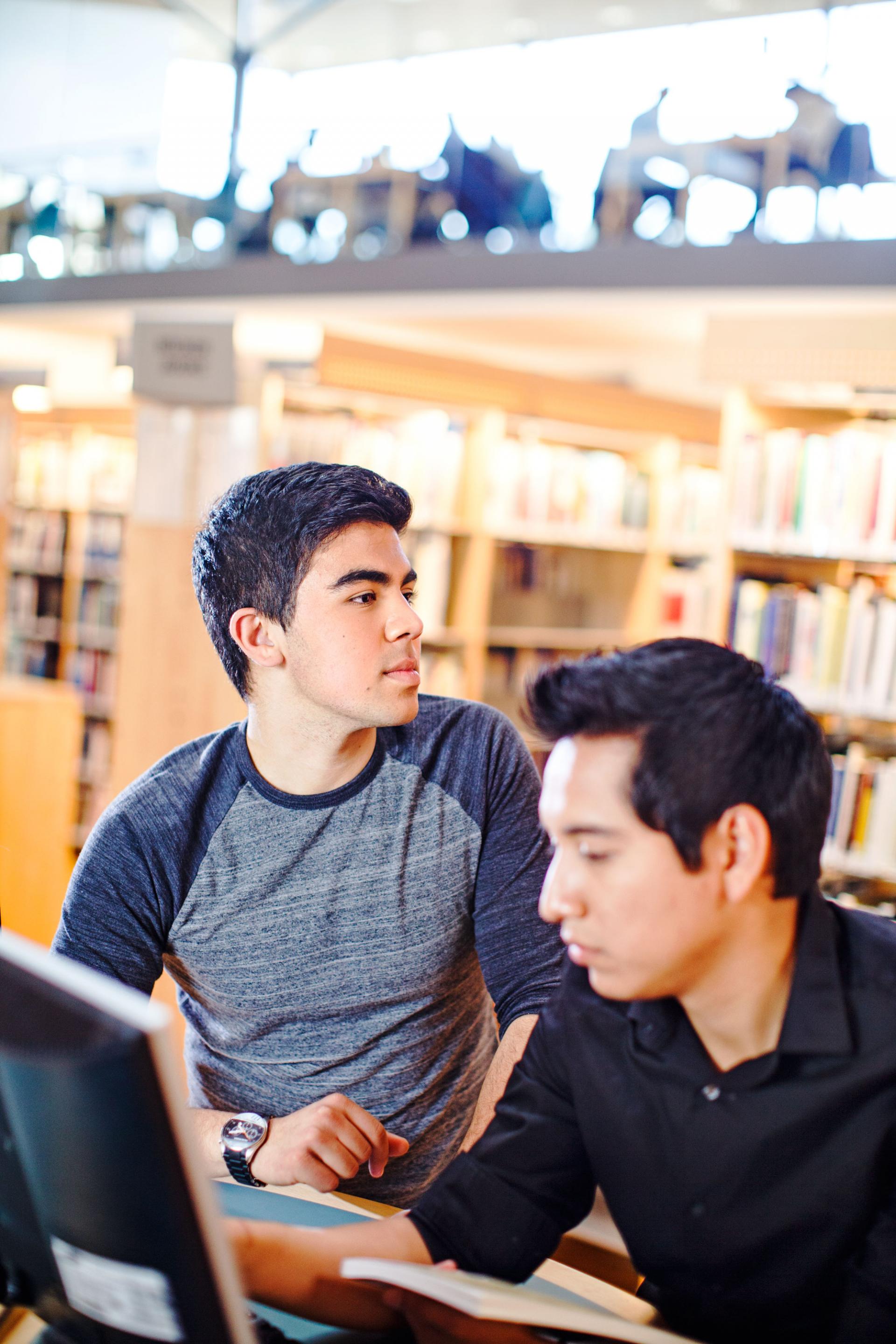 Två manliga studenter i biblioteket