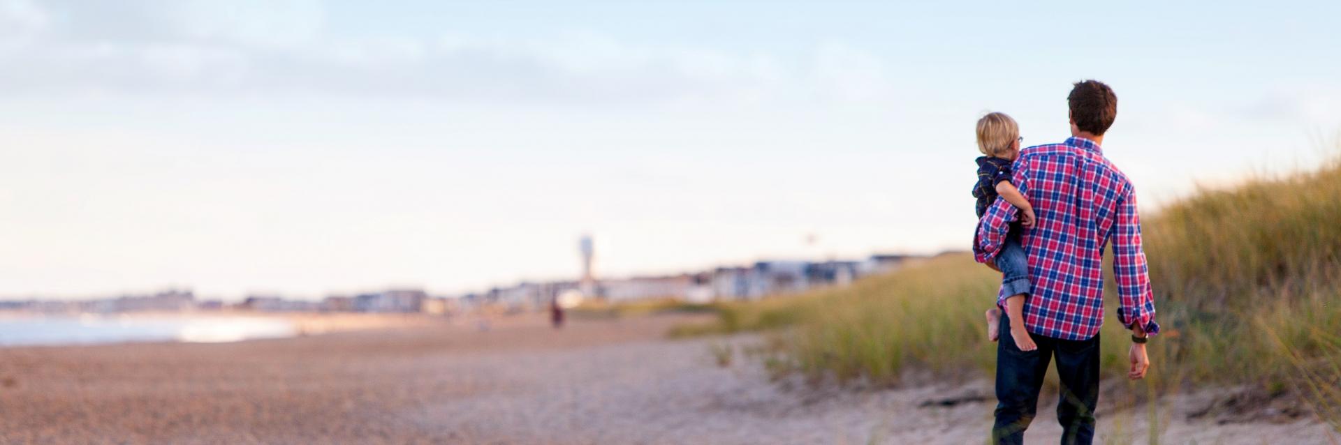 Man på strand med barn på armen