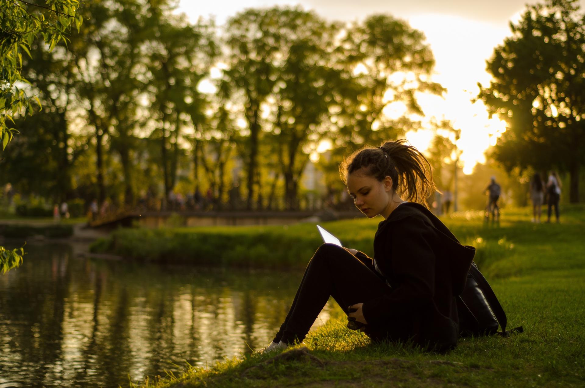 person sitter i gräset vid vatten