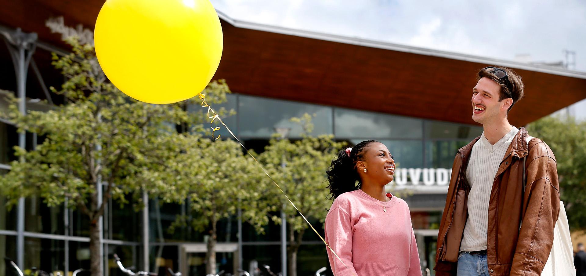 Studenterna Sharon Tenjem och Carl Wigelius med gul ballong
