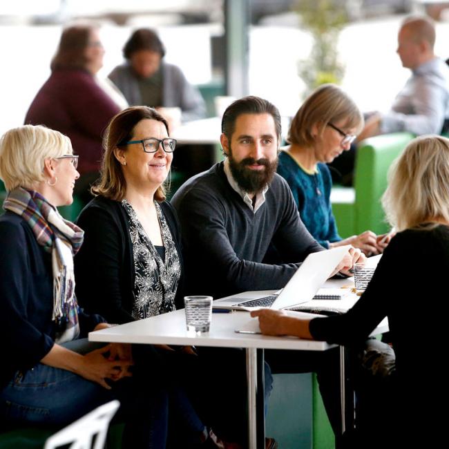 grupp med äldre studenter kring ett bord