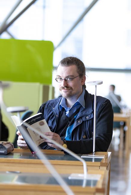 Kulturvetarstudenten Markus Helmersson läser i biblioteket