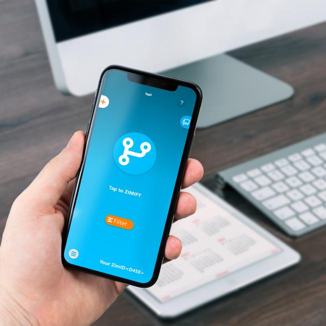 Person håller en mobil i handen med Zimify-appen på skärmen