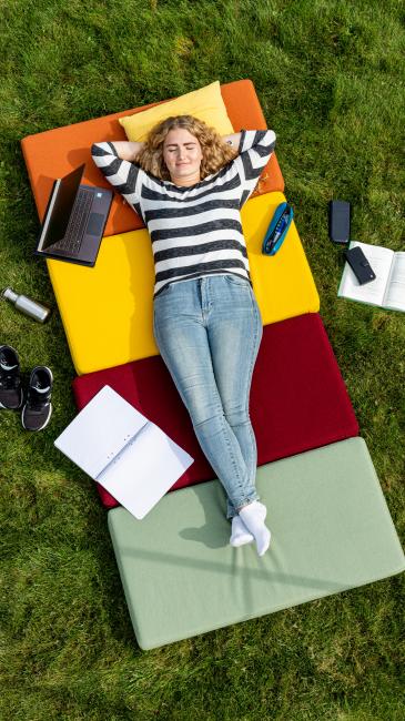 Student på rygg i gräset
