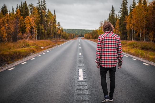 Man som gå på en öde landsväg på hösten