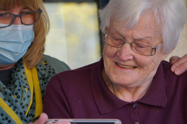 Old person with glasses with young person with face mask