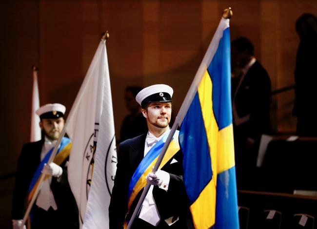 Marskalker som bär fanan för Karlstads universitet samt svenska flaggan