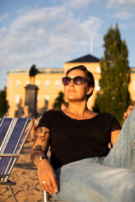 Kvinna sitter i kvällssol i Residensparken i Karlstads centrum