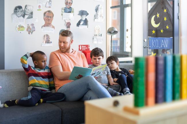 Förskollärare läser ur en barnbok för tre barn