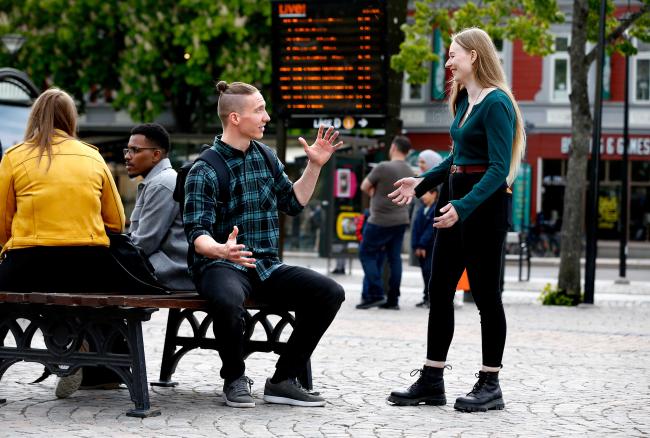 Två studenter pratar och gestikulerar på Stora torget i Karlstad centrum