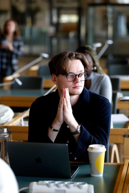 Student i biblioteket sitter och funderar i biblioteket på Karlstads universitet
