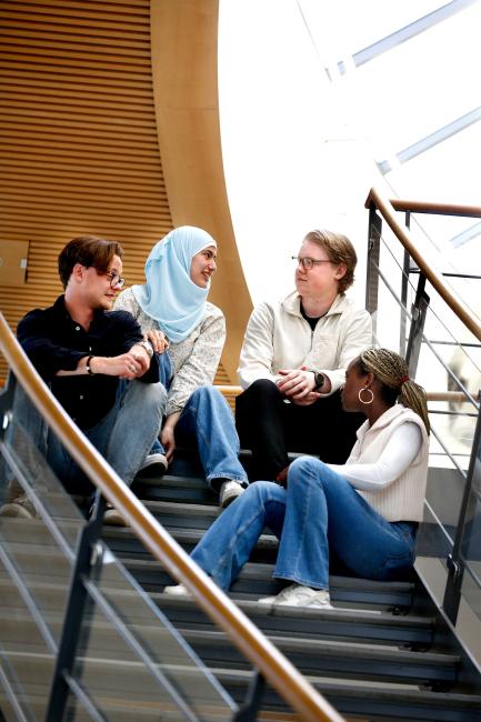 Fyra studenter sitter i en trappa och diskuterar