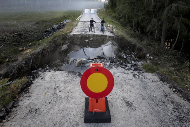 Bild på vägskylt, förbud mot trafik med fordon, framför en delvis bortspolad väg.