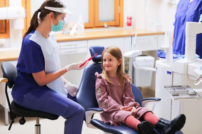 Tandhygienist visar en tandborste för en flicka i 6-årsåldern