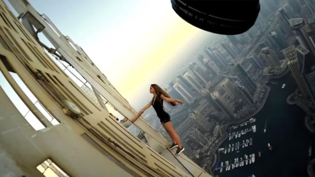Kvinna som hänger ut från ett höghus och blir fotograferad