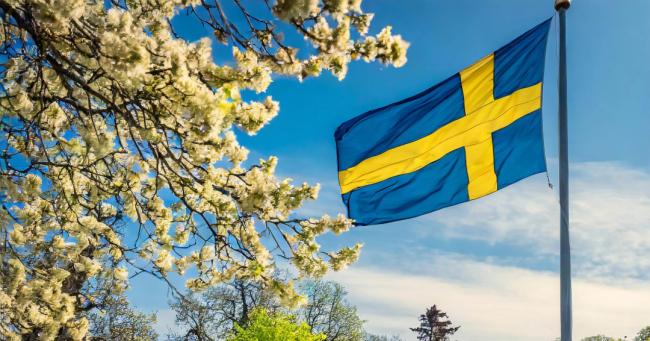Svensk flagga vajar i vinden en vårdag