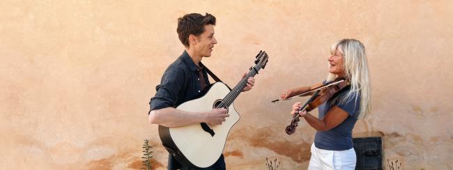 Man spelar gitarr och en kvinna spelar fiol