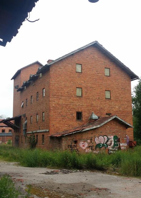 Röd tegelbyggnad med graffiti på ena väggen.