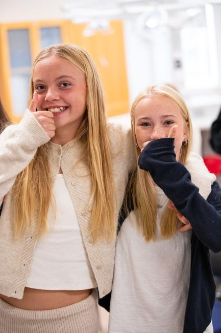 Två besökande elever under forskarfredag skrattar och gör tummen upp