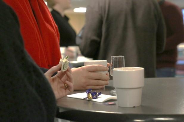 hand håller kaffekopp på bord