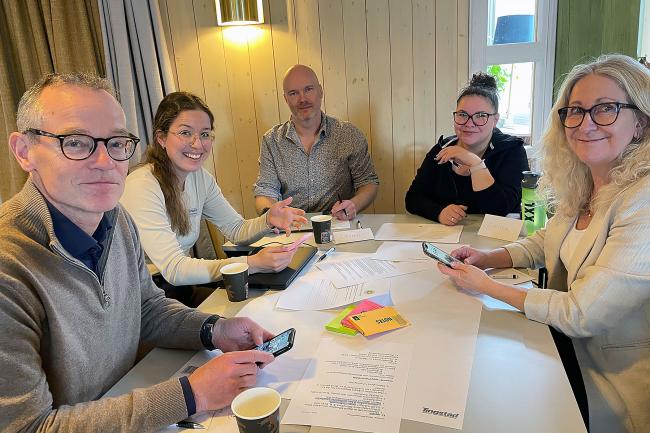 Grupp av människor sitter runt ett bord och workshopar