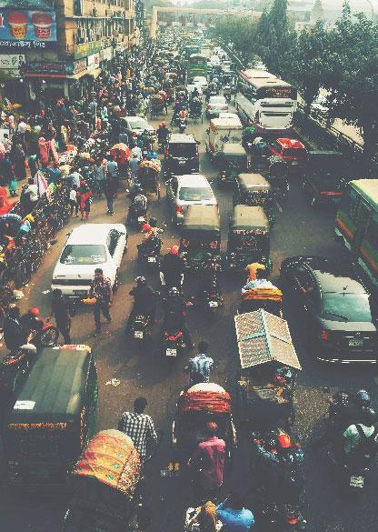 En gata med många fordon, människor och cyklar i Dhaka