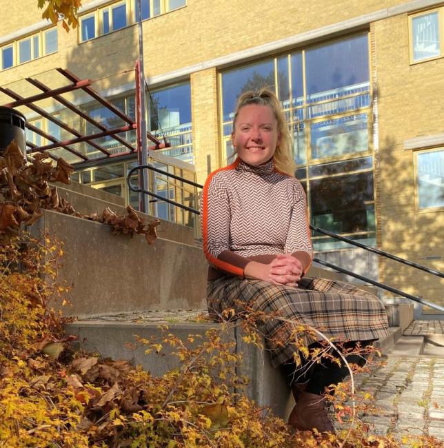 Woman sitting outside with autumn leaves