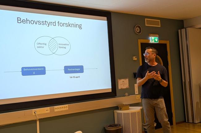Man framför skärm med presentation