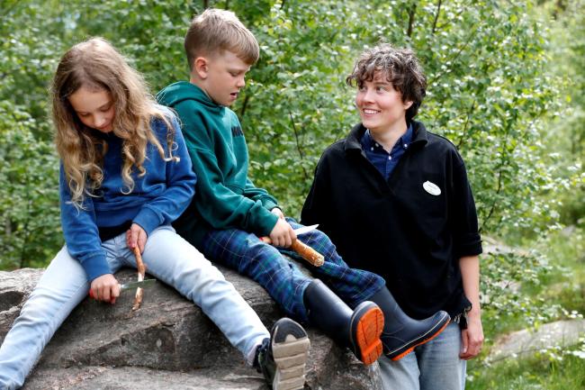 Barn i skogen tillsammans med lärare i fritidshem.