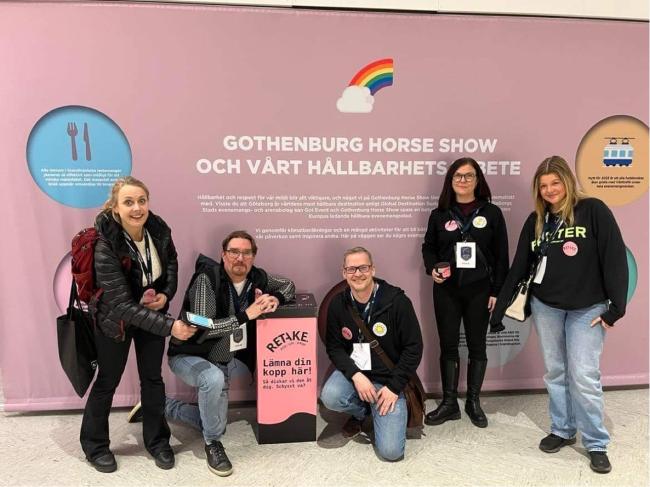 En grupp människor framför en rosa poster