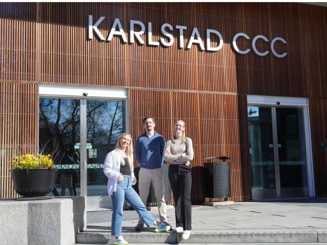 Tre medlemmar i projektgruppen framför entrén på KCCC