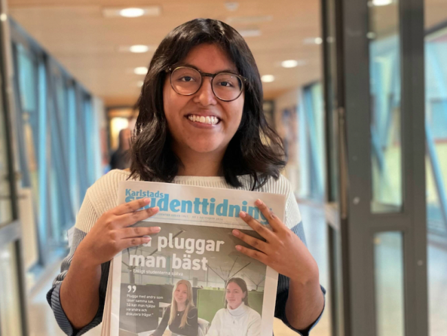 Tuva håller upp papperstidningen Karlstads studenttidning