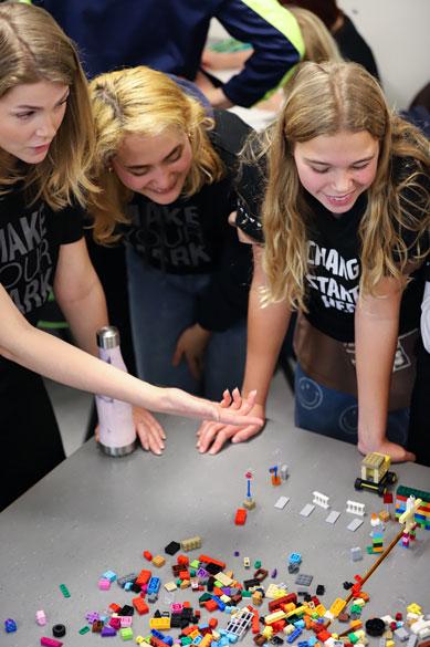 Studenter och elever i Vera-projektet står vid ett bord fylld av lego