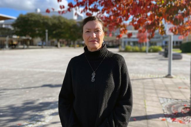 Kvinna utomhus med röda höstlöv i bakgrunden