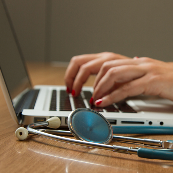 Woman typing on computer in medical surroundings