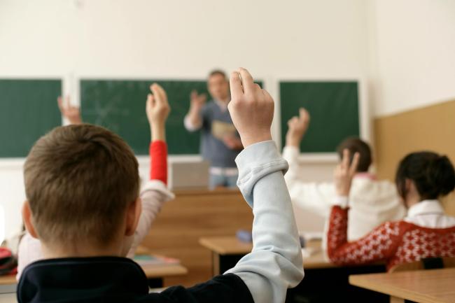 Ungdomar som räcker upp händer i ett klassrum_Avhandling om kontroversiella diskussioner om samhällsfrågor_Victoria Williamsson